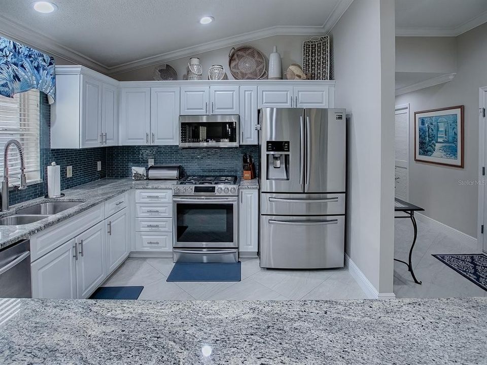 LOVELY GLASS TILE BACKSPLASH, STAINLESS APPLIANCES, AND GAS STOVE.