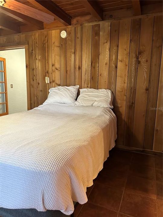 Wood clad walls and ceilings in spacious primary bedroom