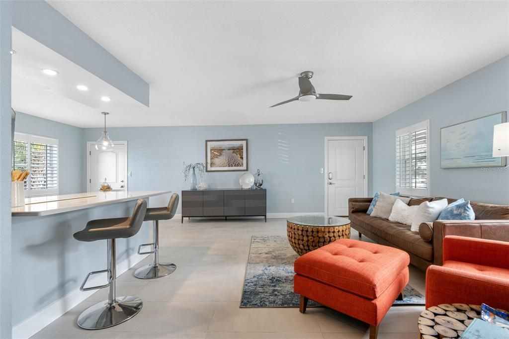 The room is painted in a soft, light blue that enhances its open and airy feel, complemented by a high ceiling with a modern ceiling fan that circulates air efficiently throughout the space,