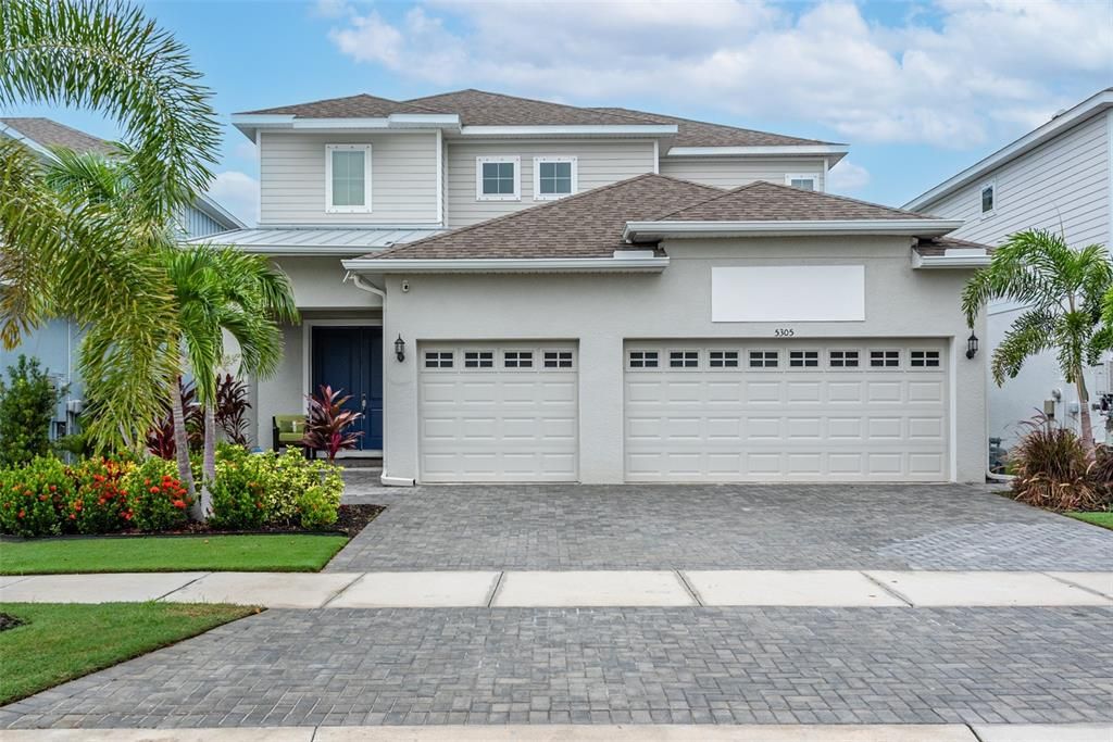 Front view of waterfront pool home with 3 car garage.