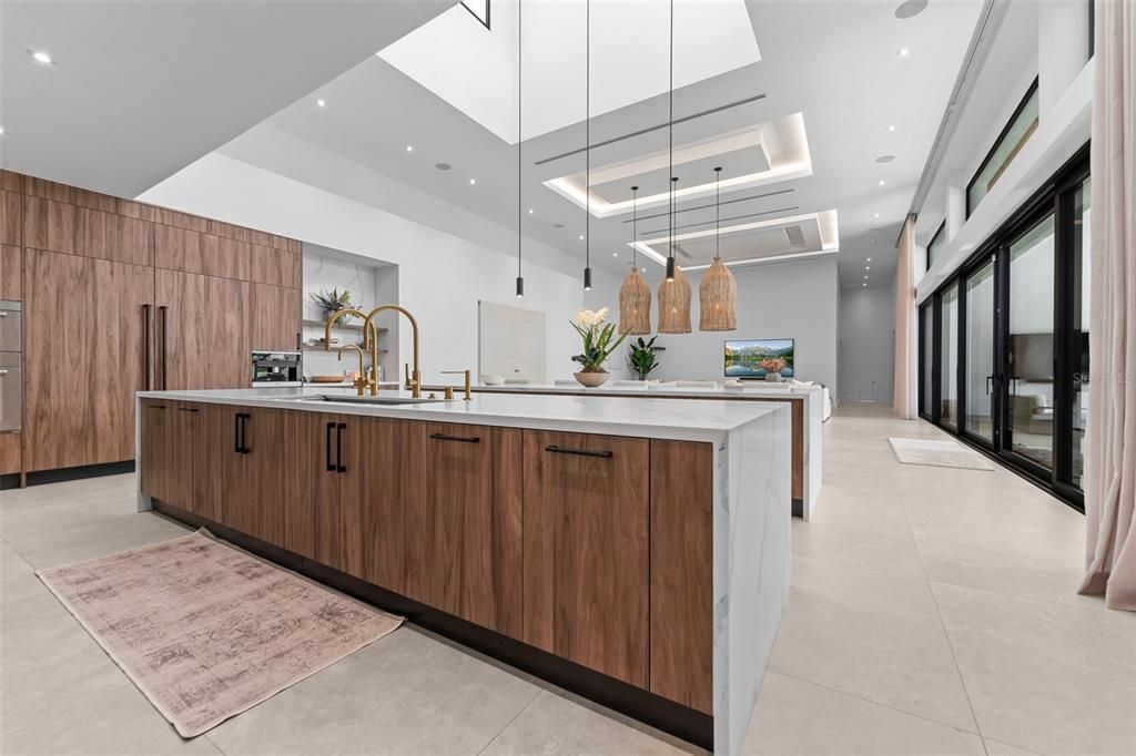 Natural light beaming from above kitchen island window with pendant lighting and led lights throughout the kitchen for night time lights. Custom kitchen cabinets are imported from Italian brand Cucina Lube.