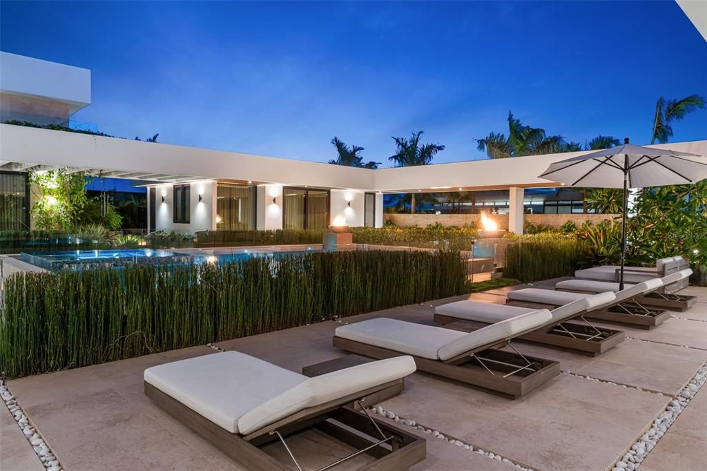 Fire pits by the pool surrounded by luscious tropical landscaping.