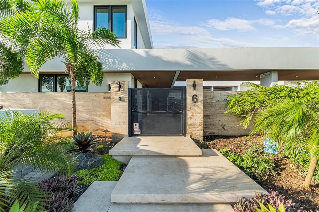 Staggered floating stairs at the entrance of DCE Lot 6 surrounded by lush landscaping and an iron metal gate at the entrance.