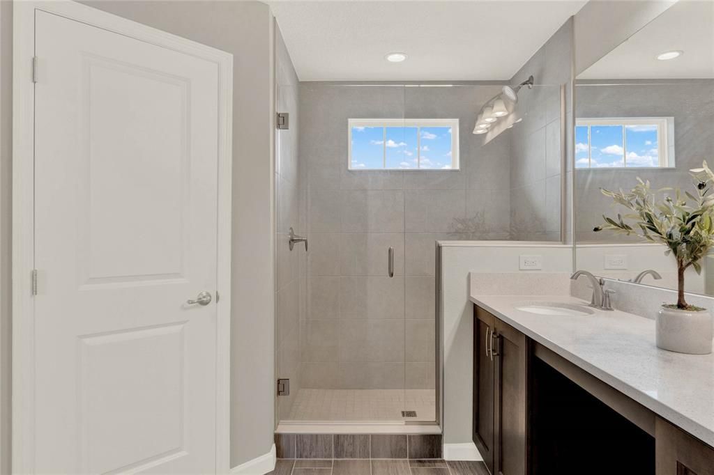 Gorgeous quartz countertops and walk-in shower with floor to ceiling tile