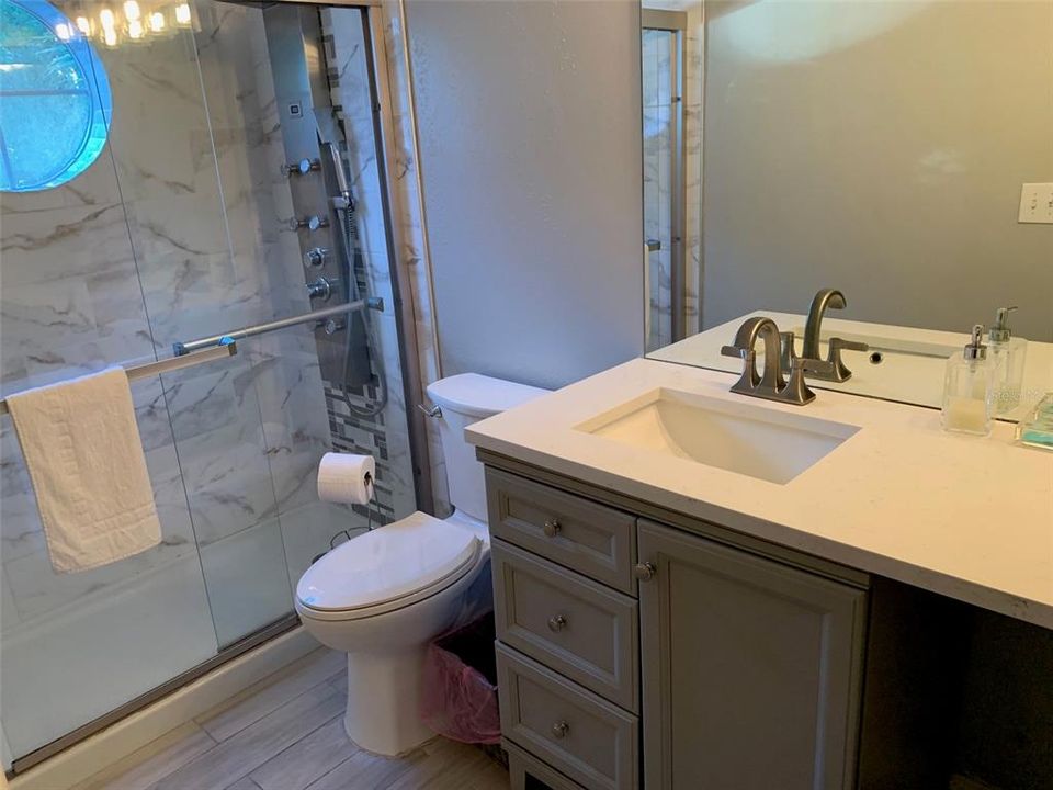 Remodeled en-suite bathroom in second primary bedroom #2.  Tiled shower and quartz vanity