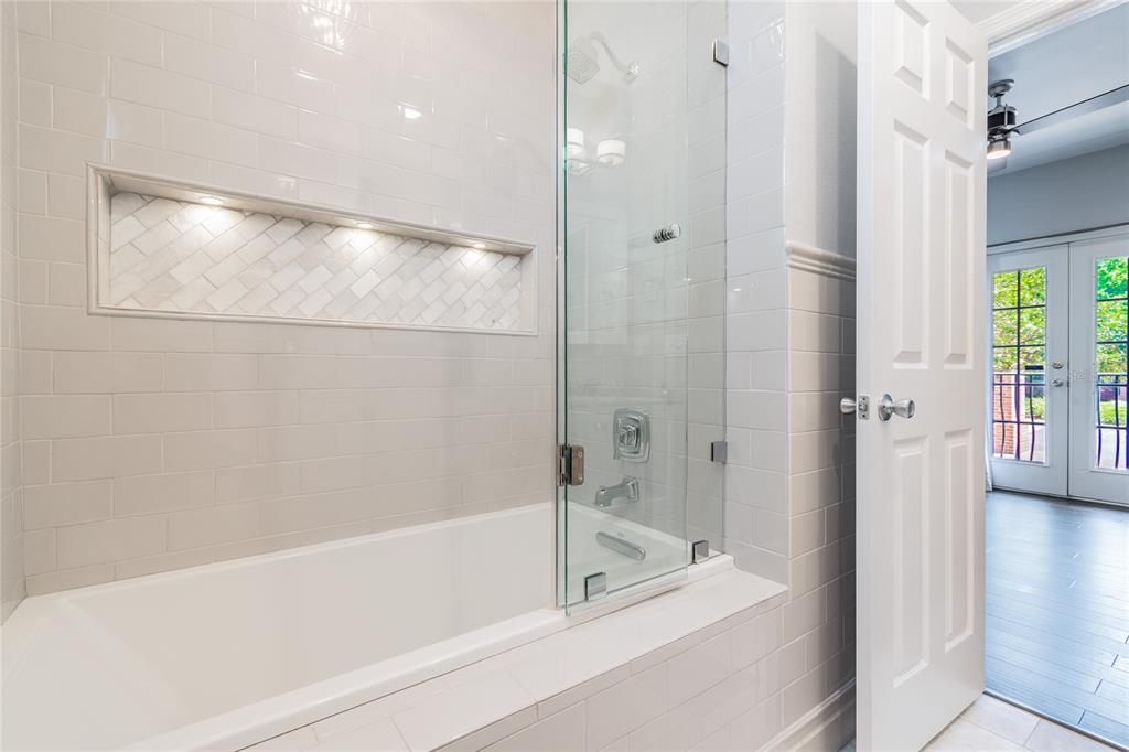 Illuminated niche in downstairs bathroom with hinged seamless glass door.