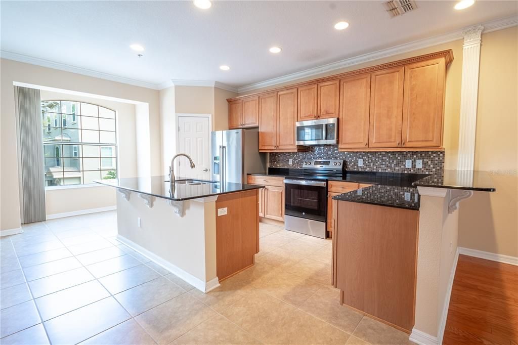 Up on the second floor, you'll find the heart of the home—a bright and open main living area with elegant crown molding throughout. The spacious kitchen is perfect for both cooking and entertaining, featuring solid wood cabinets, gleaming quartz countertops, and an island with a breakfast bar. A suite of stainless steel appliances, including a brand new range (with air fryer), make meal prep a breeze, while the walk-in pantry offers plenty of storage. There's plenty of space for your breakfast table beside the window.