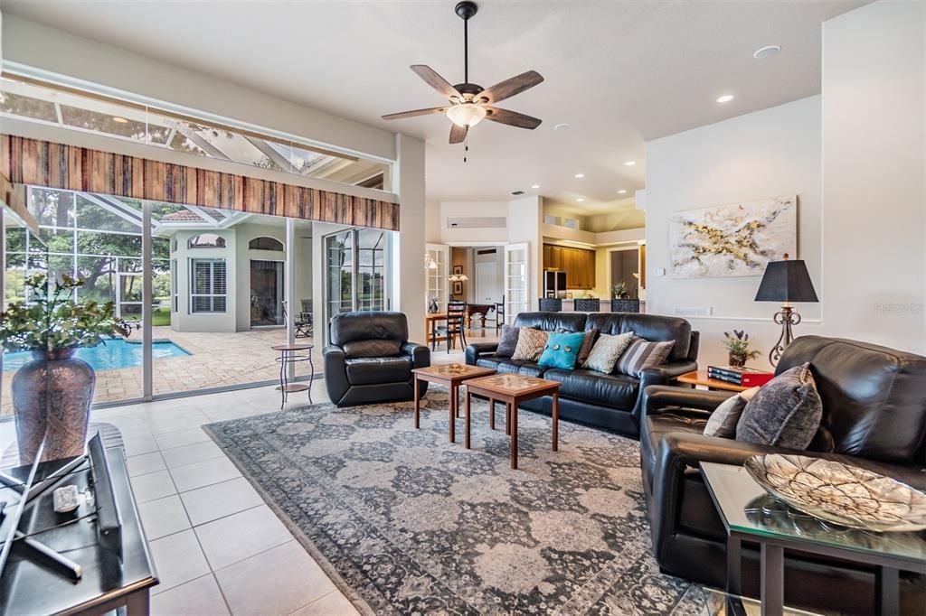 Family room with ceiling fan, Fireplace double sided, Tile Flooring overlooking the pool/spa and water view.