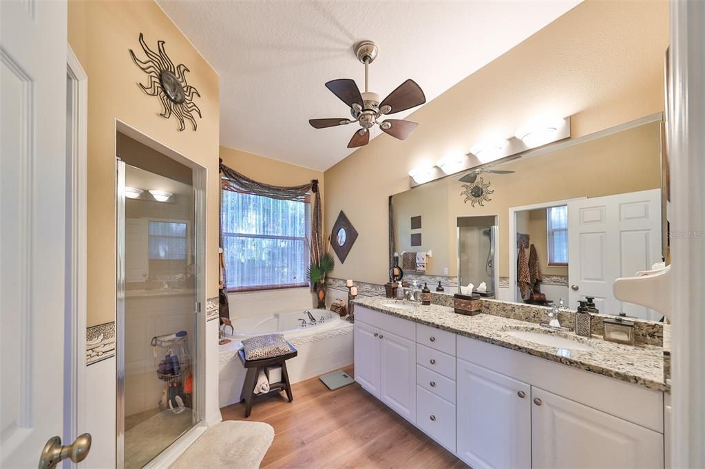 Primary suite bathroom with double sink vanity, tub and separate shower.