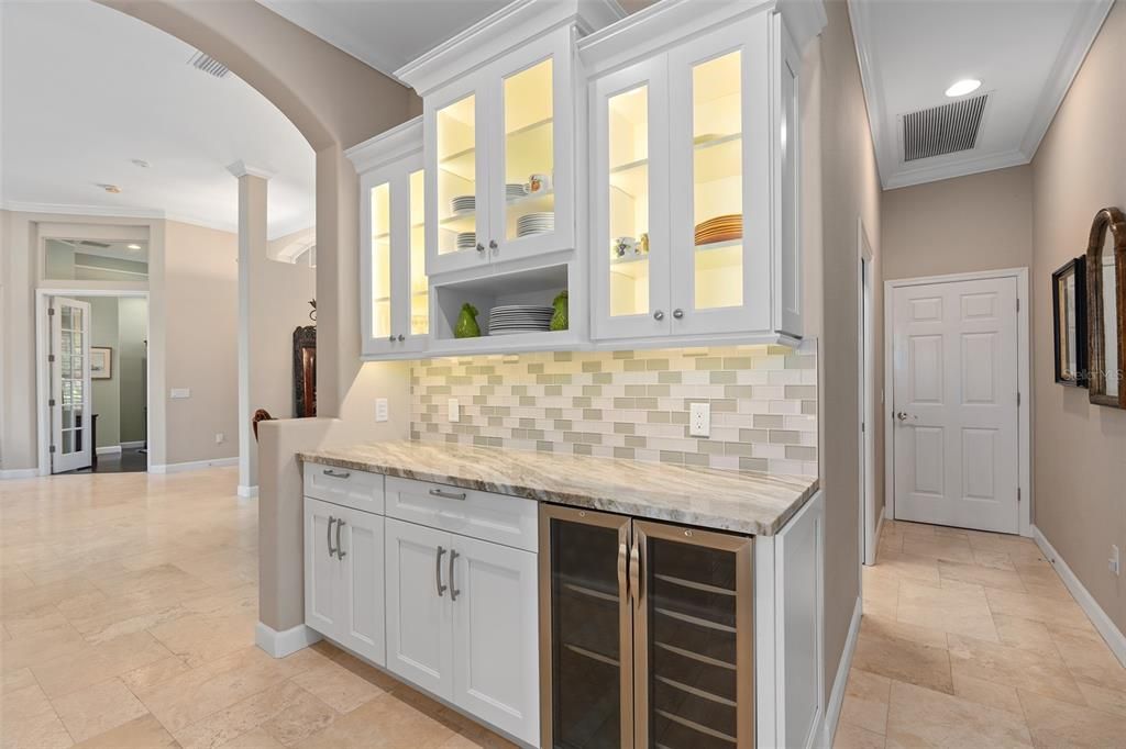 custom butler pantry with dual zone fridge, beautiful shaker cabinets, stone countertop, glass backsplash and custom lighting