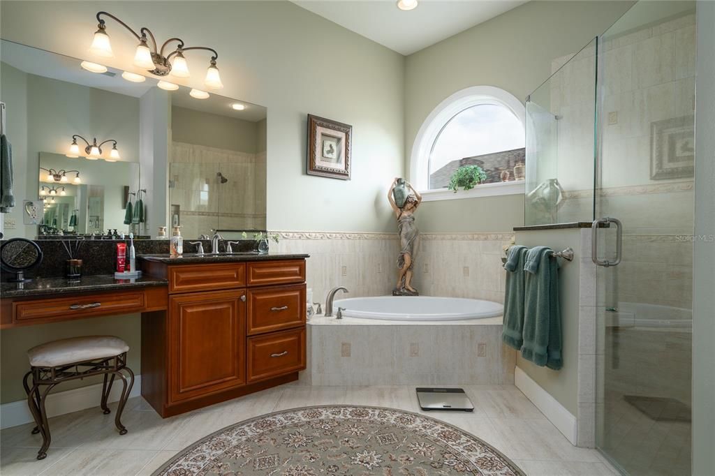 The granite and cabinets of dual vanities match the rest of the home. This spacious ensuite bath also features a welk-in shower, garden tub, and plenty of natural lighting.