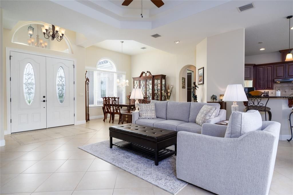 Main living area towards entrance, dining room, and kitchen (left to right). Upgraded paddle fans with wall to wall controls and multiple dimmer switches throughout.