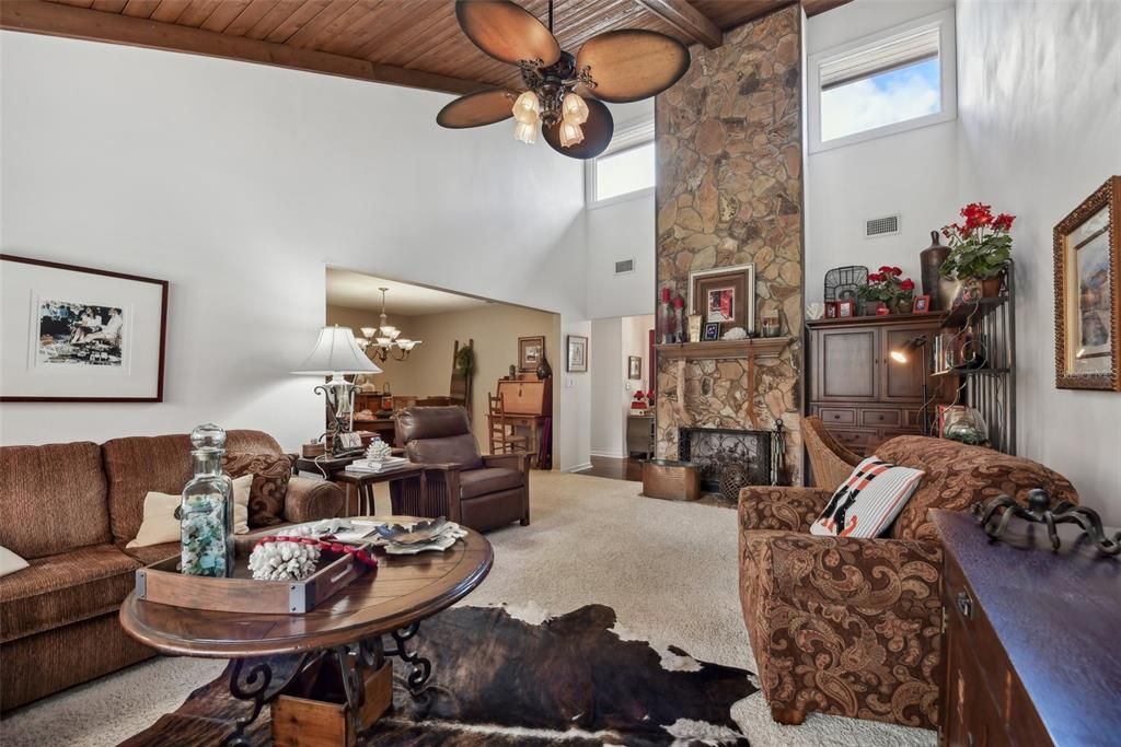 SOARING CEILINGS in the Living Room and a STONE FRONT, WOOD BURNING FIREPLACE that extends all the way up to the Highest Point of the Vaulted Ceilings. WOOD CEILING PLANKS and WOOD BEAMS that run along the MAIN LIVING AREA CEILINGS are highlighted by ALL OF THE NATURAL LIGHT that POURS into the MAIN LIVING AREAS OF THE HOME through LARGE WINDOWS THROUGHOUT