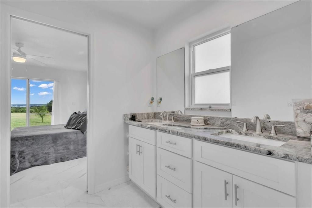 Primary Bathroom with Tall Cabinets: Marble Looking Granite Counter, White Shaker Cabinets with Tubular SS Handles & Dual Sinks