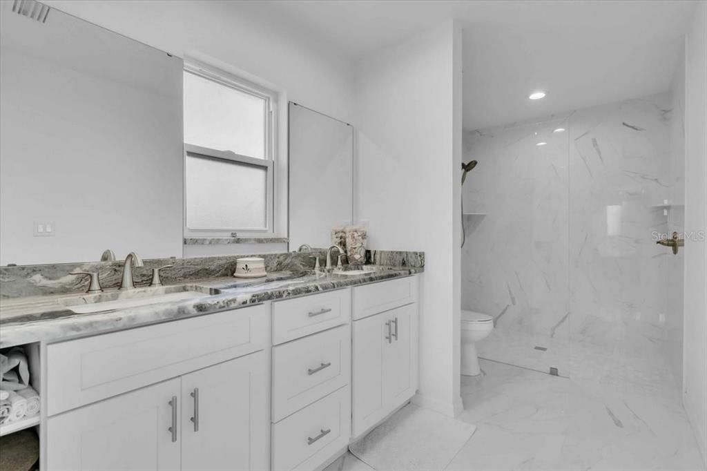 Primary Bathroom with Tall Cabinets: Marble Looking Granite Counter, White Shaker Cabinets with Tubular SS Handles & Dual Sinks