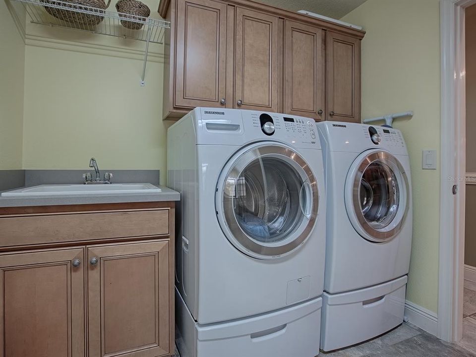 LAUNDRY ROOM WITH FRONT LOAD WASHER AND DRYER THAT DO CONVEY WITHTHE HOME, BUILT-IN SINK AND LOTS OF EXTRA CABINETS.