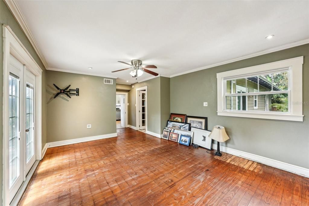 Primary bedroom - french doors lead to outdoor slate patio.  Floors have been stripped to original wood floors ready for your finish touch.