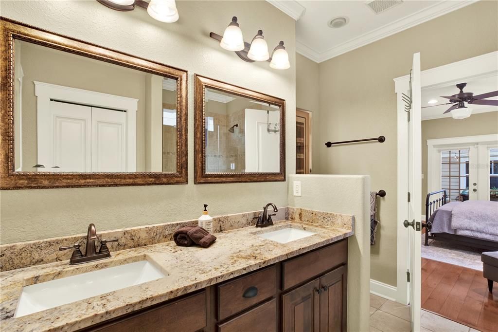 Warm woods and natural stone flow into the downstairs primary bathroom