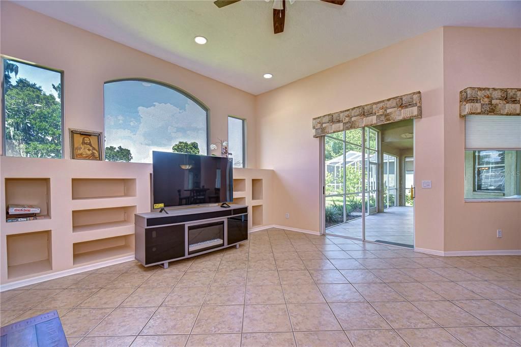 High ceilings and oversized windows create a bright and airy family room, complete with built-in shelving and double sliding doors!