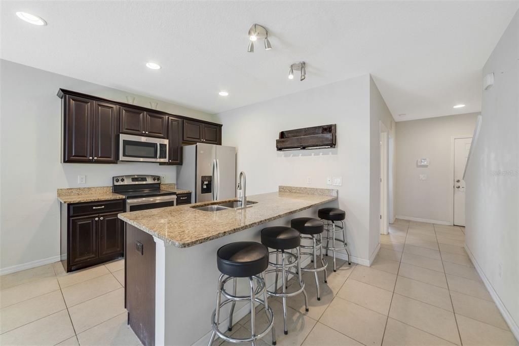 The natural flow from the foyer brings you into a well appointed kitchen where the home chef will enjoy rich cabinetry, STAINLESS STEEL APPLIANCES, granite counters, a pantry for ample storage and breakfast bar seating under pendant lighting for casual gatherings.