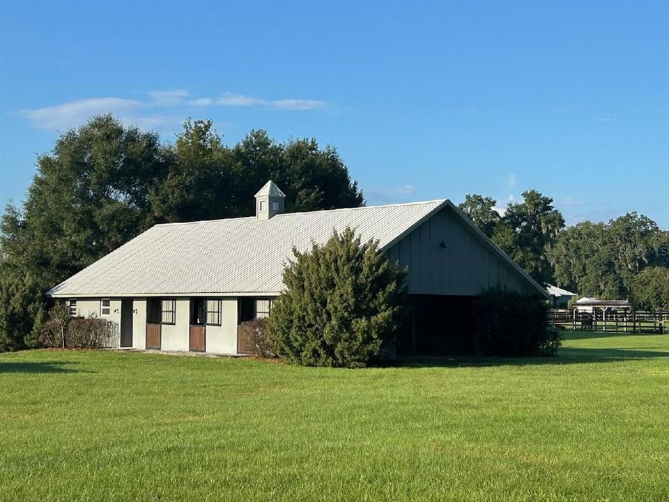 Back of barn, stalls open to center-aisle with dutch doors off back.  You could add paddocks off the barn if desired.