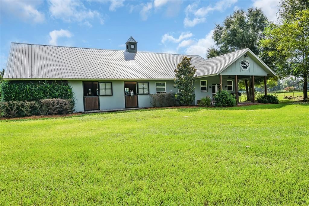 Beautiful barn built in 2018, office, bath, open porch.  Stalls open to center-aisle and outside, notice the plexi-glass top dutch doors with happy horses.