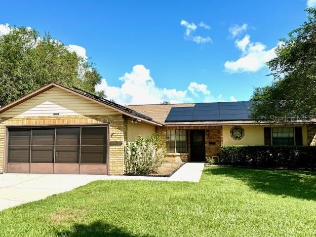 Front of home with solar panels, and concrete walkway up to front door