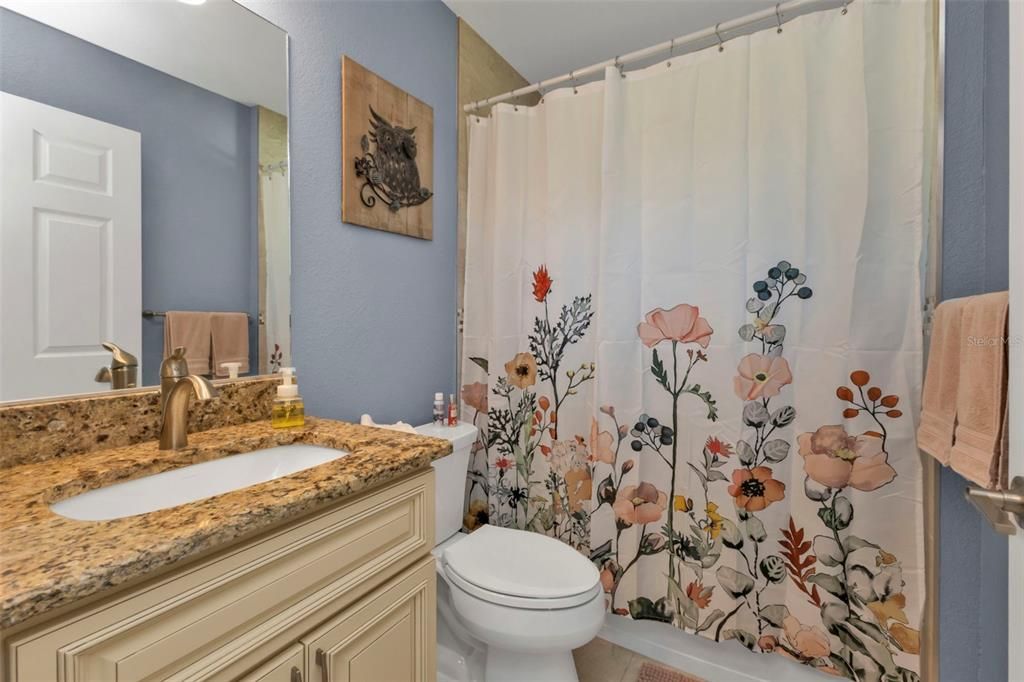 Guest bath features single vanity and shower/tub combo.