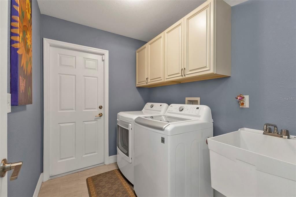 Laundry room with washer and dryer included, utility sink and additional cabinets.