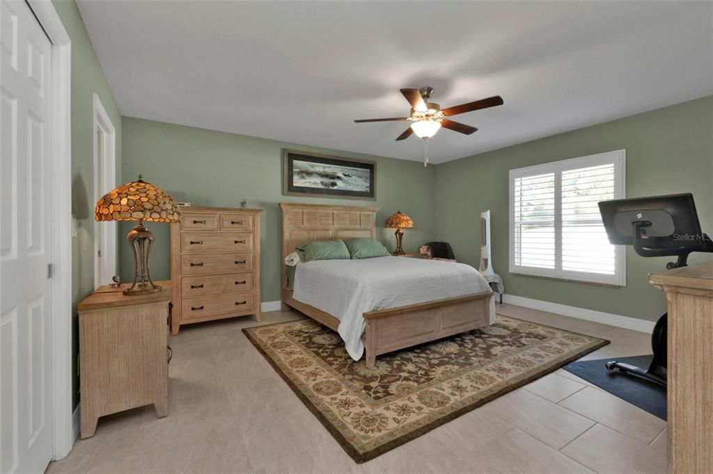 Master bedroom is spacious with walk in closet, porcelain tile flooring, plantation shutters  and ceiling fan.