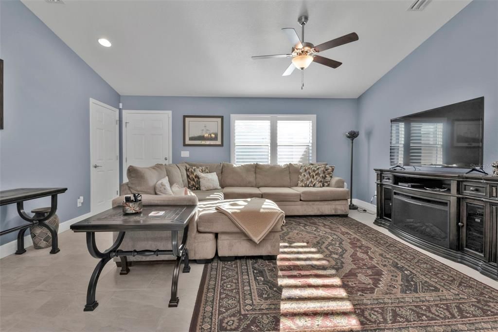 Living room with porcelain tile throughout with plantation shutters.