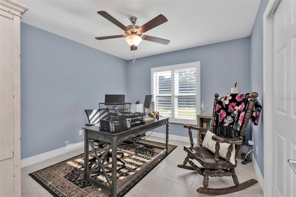 Guest bedroom 2 with ceiling fan, closet and plantation shutters.