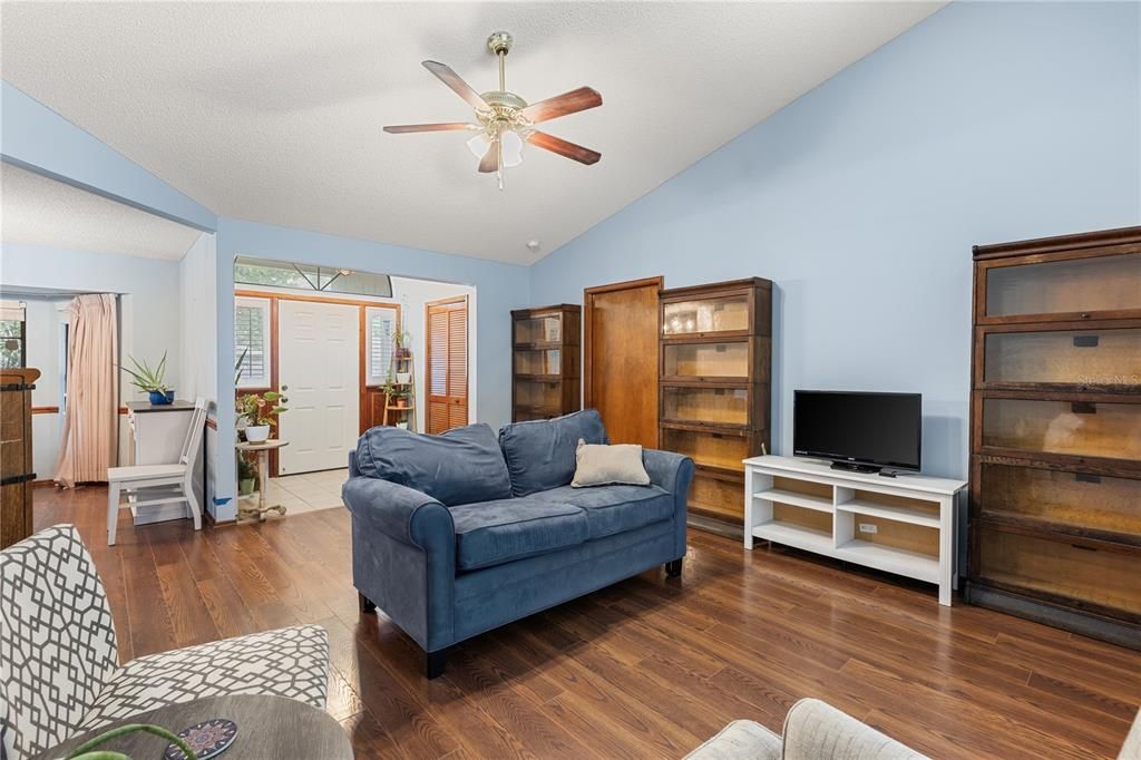 Family Room off the front foyer featuring vaulted ceilings, wood floors, and a sliding glass door to the back lanai.