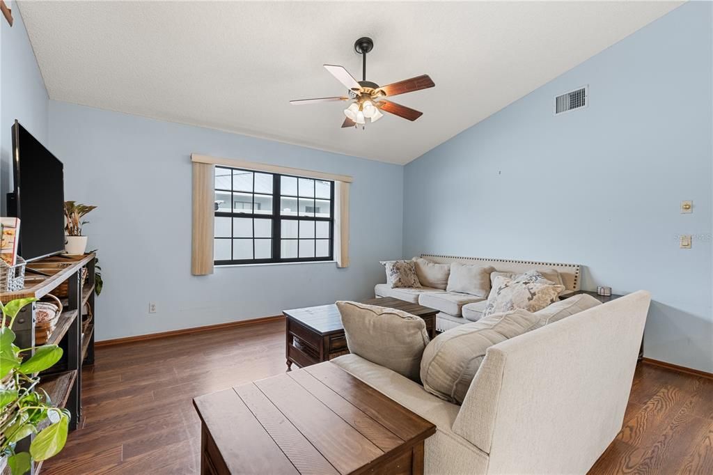 Living Room off the kitchen featuring a large window, and wood flooring.