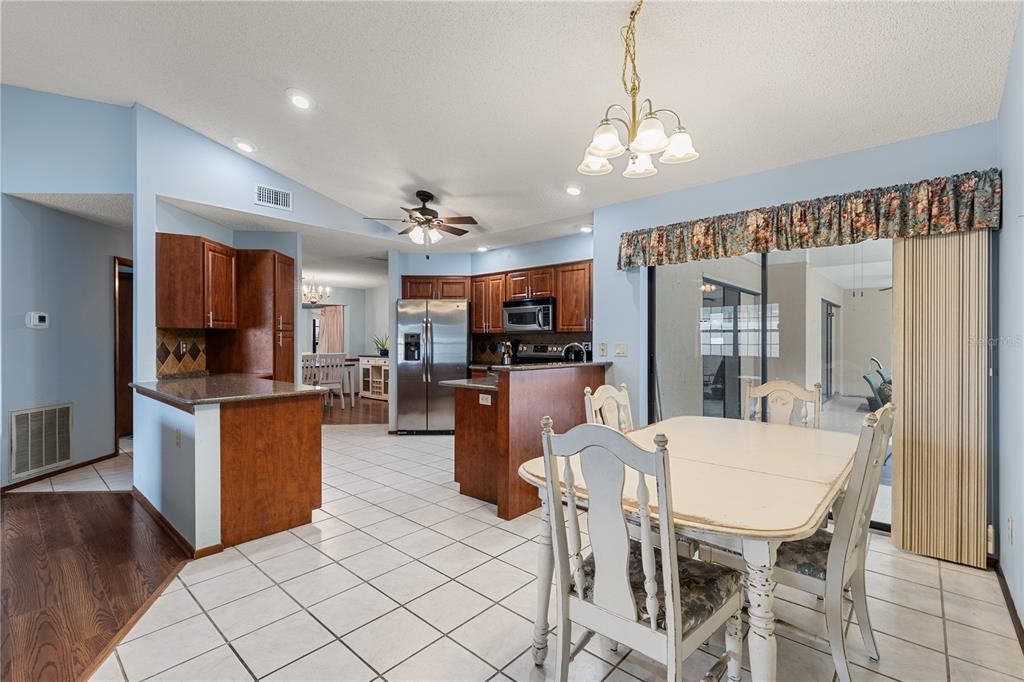 Spacious kitchen featuring wood cabinets, quartz countertops, stainless steel appliances, and a dinette.