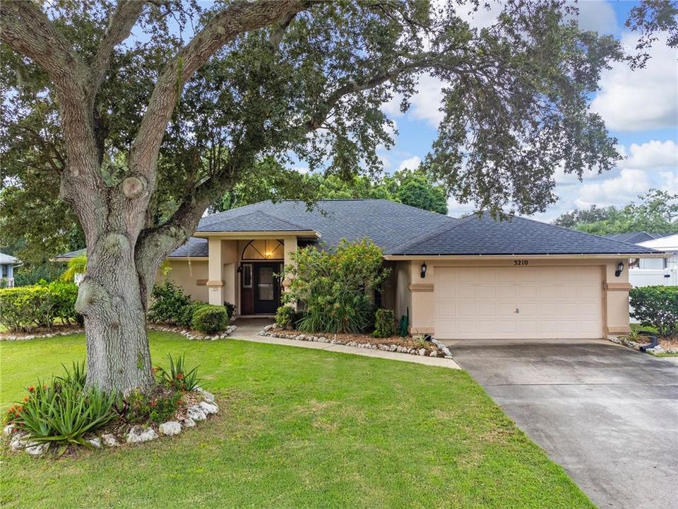 Front elevation showing the large driveway, mature landscaping, and front entryway.