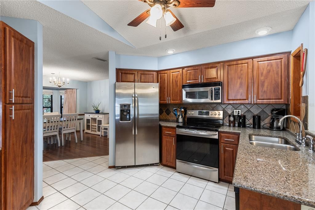 Spacious kitchen featuring wood cabinets, quartz countertops, stainless steel appliances, and a dinette.