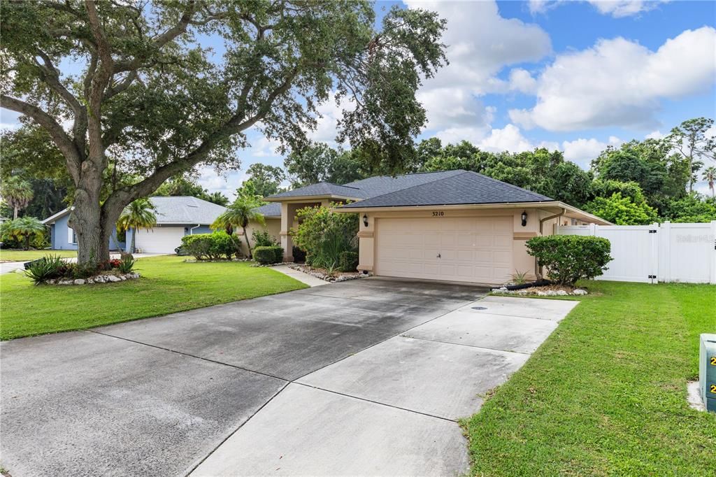 Front elevation showing the large driveway, mature landscaping, and front entryway.