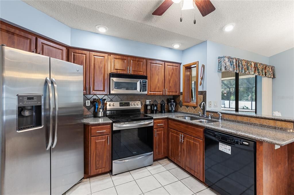 Spacious kitchen featuring wood cabinets, quartz countertops, stainless steel appliances, and a dinette.