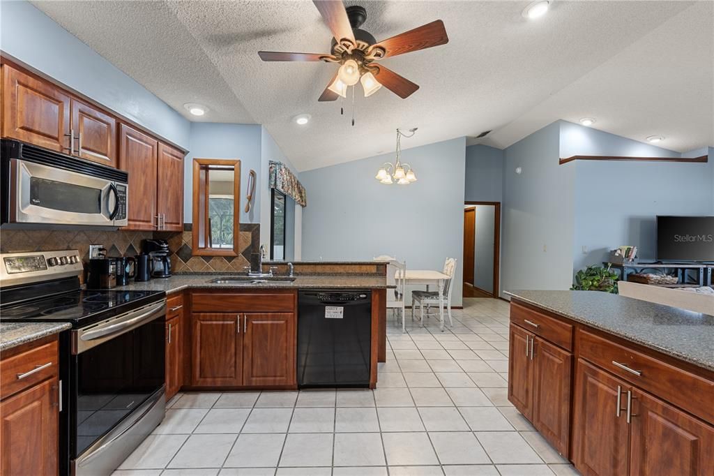 Spacious kitchen featuring wood cabinets, quartz countertops, stainless steel appliances, and a dinette.