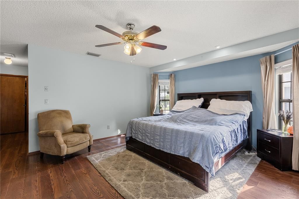 Owners suite featuring wood floors, sliding glass doors to the screened-in lanai, walk-in closet, and ensuite bathroom.