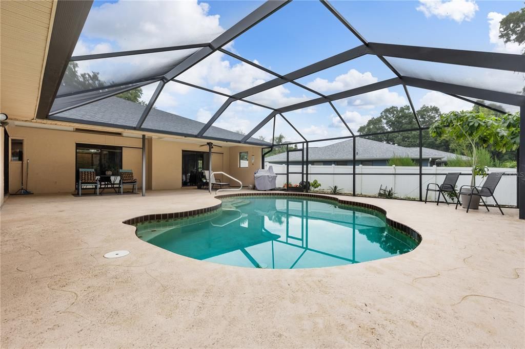 Spacious screened-in lanai featuring a headed saltwater pool, and views of the fenced-in back yard.