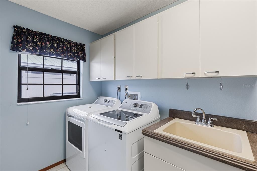 Laundry room featuring ample cabinetry and a drop sink.