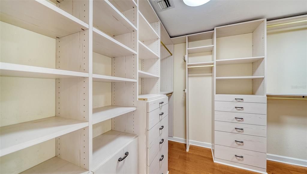 Walk-in closet with built in shelving in primary bedroom.