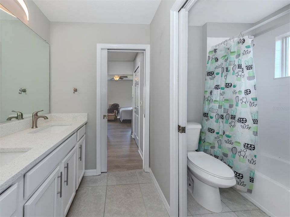 The Jack and Jill bath has been beautifully updated with quartz countertops, solid wood cabinetry, and pocket door to close off the full tub and water closet.