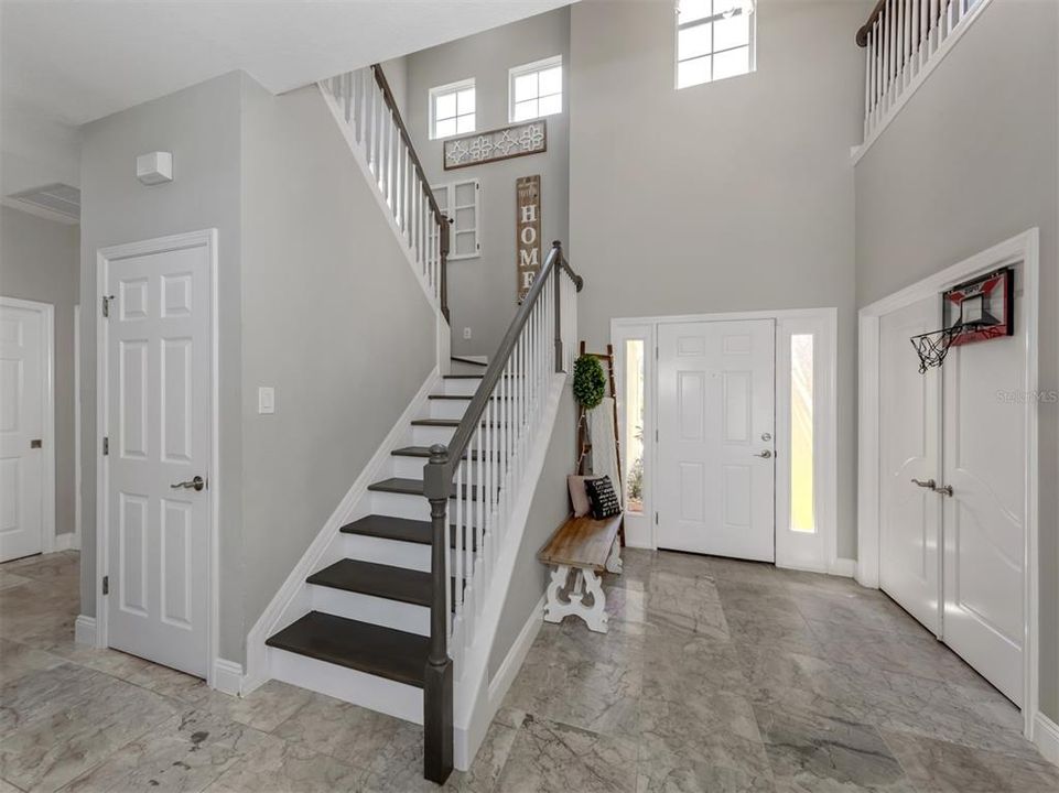 Looking back at the front door, den, under stairway storage, and stairs leading to additional bedrooms