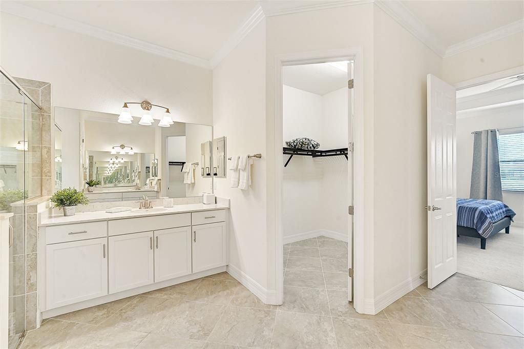 Primary bathroom with two separate vanities, two walk-in closets, bathtub and separate shower.