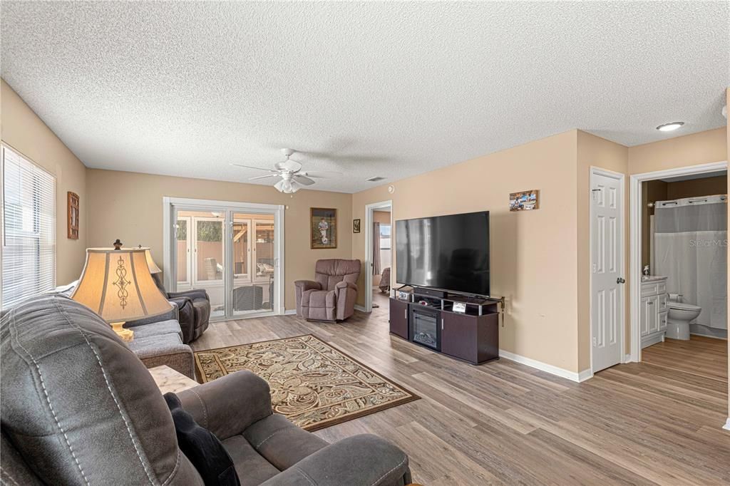 LIVING ROOM LOOKING TO THE REAR ENCLOSED LANAI. THE GUEST BEDROOM AND BATHROOM ARE OFF TO THE RIGHT IN THIS PHOTO