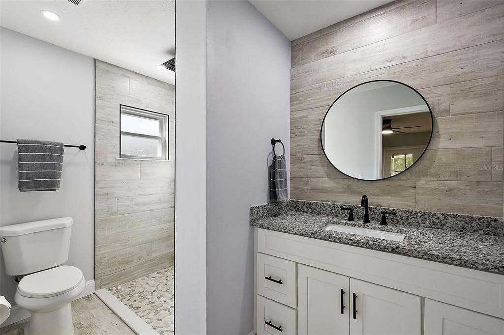 Primary en-suite bath with pebble stone shower and granite countertop