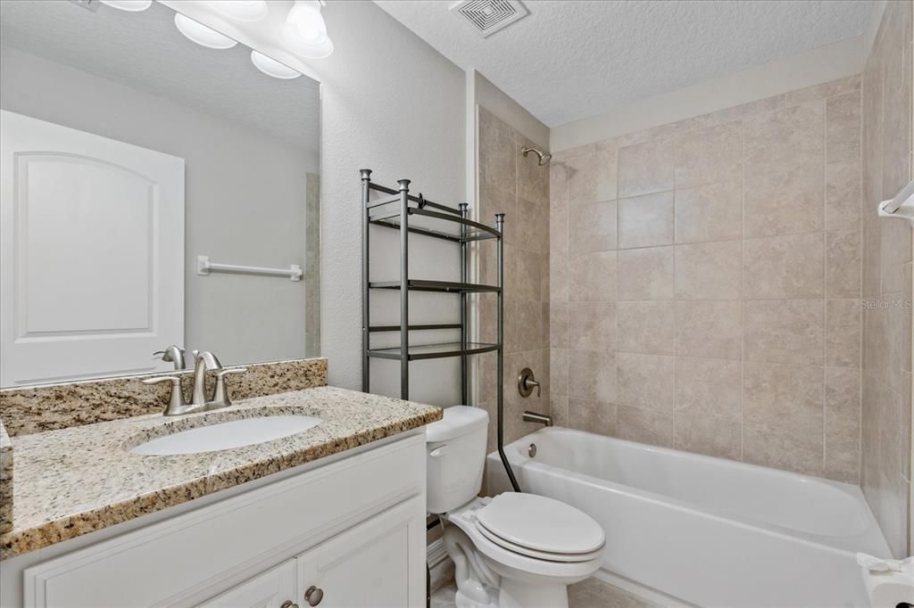 Guest bathroom with tiled shower and granite countertop